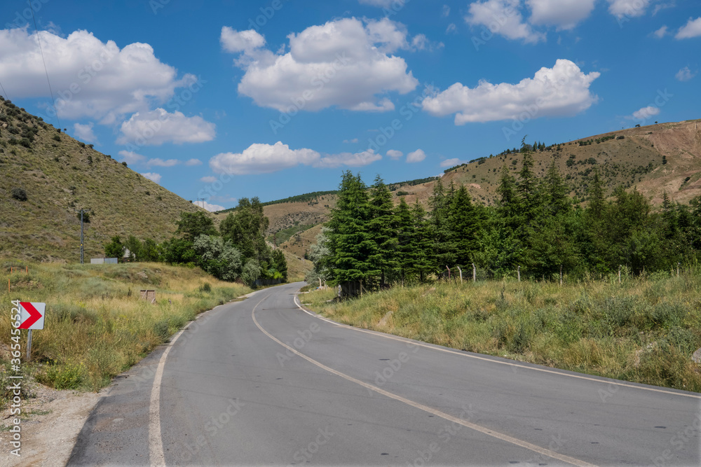 asphalt road meandering hills blue sky