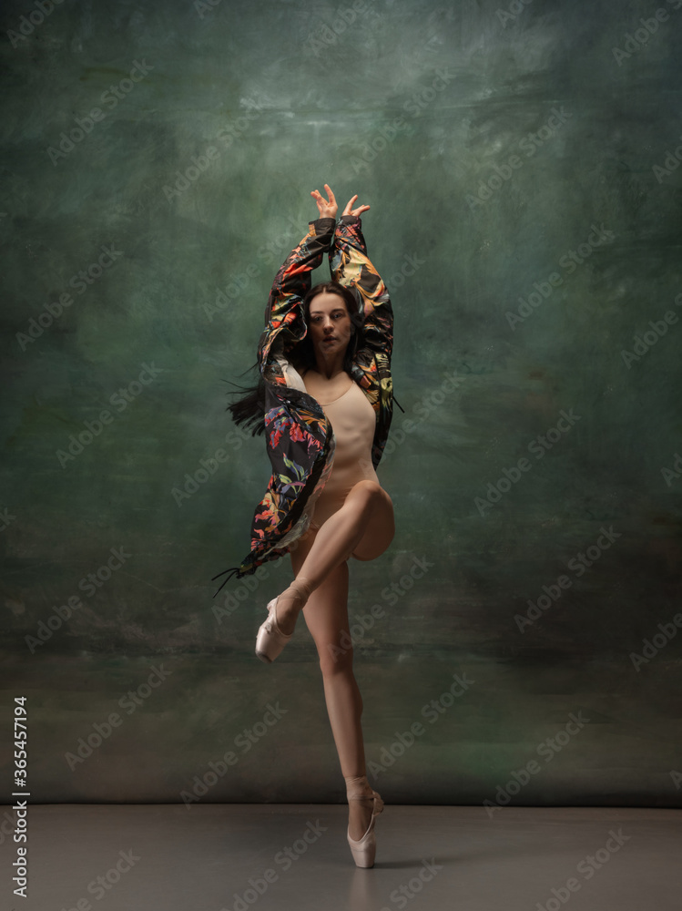Fashionable. Graceful classic ballerina dancing on dark studio background. Bright coat. The grace, artist, movement, action and motion concept. Looks weightless, flexible. Fashion, style.