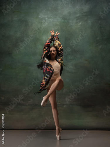 Fashionable. Graceful classic ballerina dancing on dark studio background. Bright coat. The grace  artist  movement  action and motion concept. Looks weightless  flexible. Fashion  style.