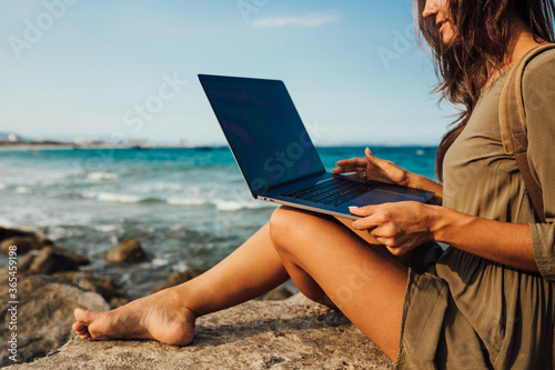 Young woman blogger working remotely with a laptop using the internet. Work on vacation while traveling. Freelance concept