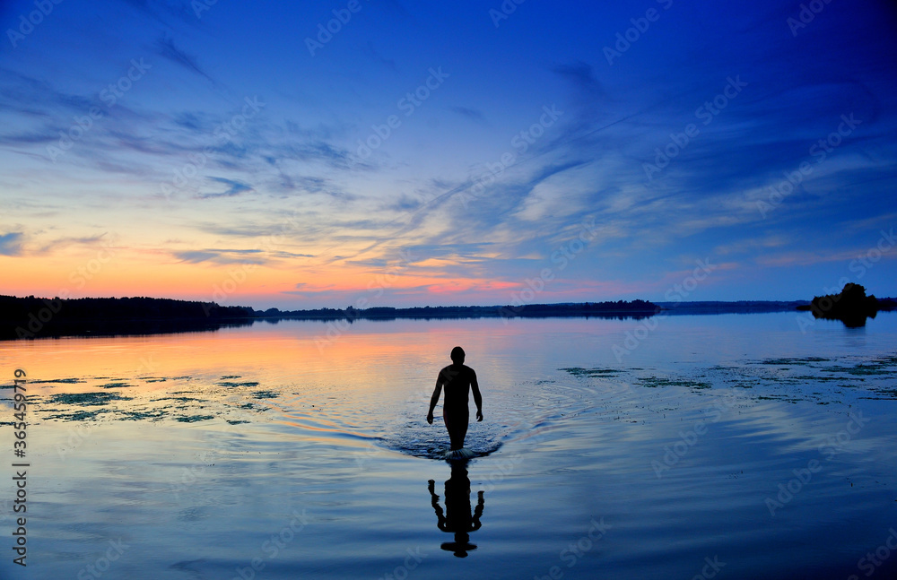  Man exiting water.Lake.Sunset.
