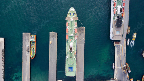 Aerial view of large cargo ship taking cargo and many small boats parked in port