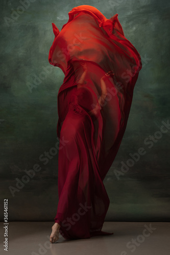 Fire flame. Graceful classic ballerina dancing on dark studio background. Deep red cloth. The grace, artist, movement, action and motion concept. Looks weightless, flexible. Fashion, style.