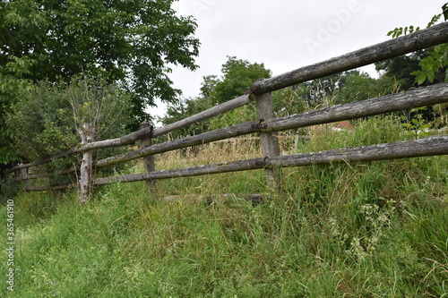An old wooden fence manually made from trunks of small trees or from branch wood near tourist path.