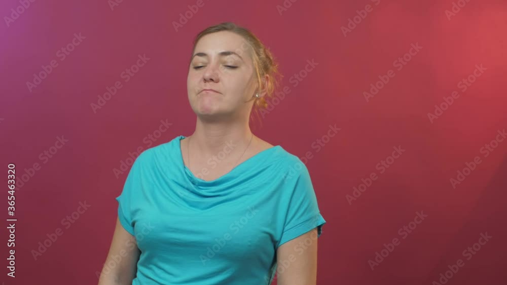 serious lady in blue t-shirt looks straight and nods standing against pink studio background close view serious lady in blue t-shirt looks straight and nods standing against pink studio background close view