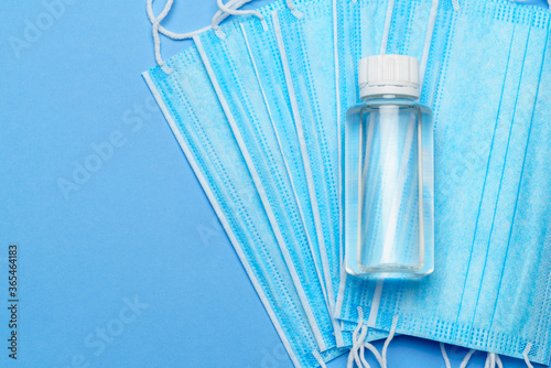 bottle of lotion, sanitizer or liquid soap and protective mask over blue background - flat layout