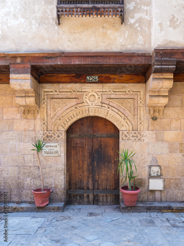 Facade of old stone bricks decorated wall with arched wooden door, Entrance of old Ottoman historic house of Moustafa Gaafar Al Selehdar, Moez Street, Old Cairo, Egypt photo