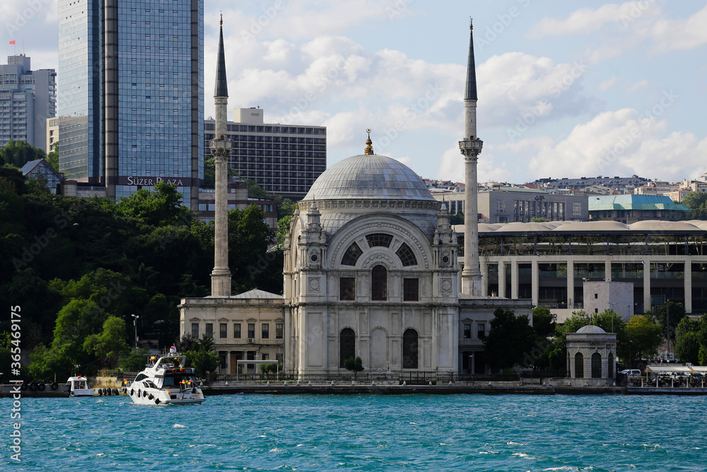 Naklejka premium A modern speedboat is seen next to the Dolmabahce mosque in a photo taken from a ferry in Bosporus strait, Istanbul, Turkey.