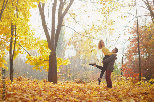 Young happy couple relaxing and loving in the autumn forest at sunset. © Myshkovskyi