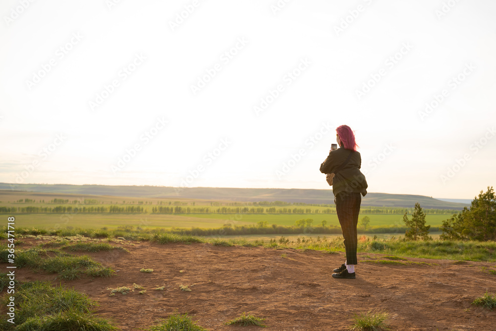 Beautiful girl takes pictures of the sunset 