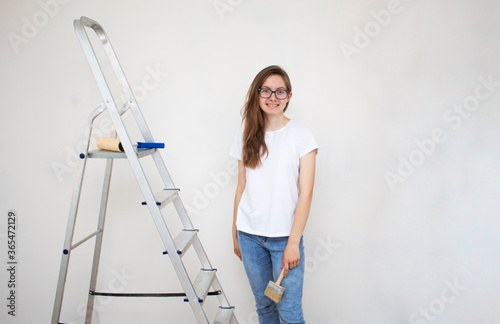 A beautiful blonde with a brush for painting walls and a stepladder
