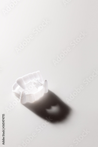 Vampire Dracula toy teeth with creepy shadow on white background with copy space. Creative concept for Halloween