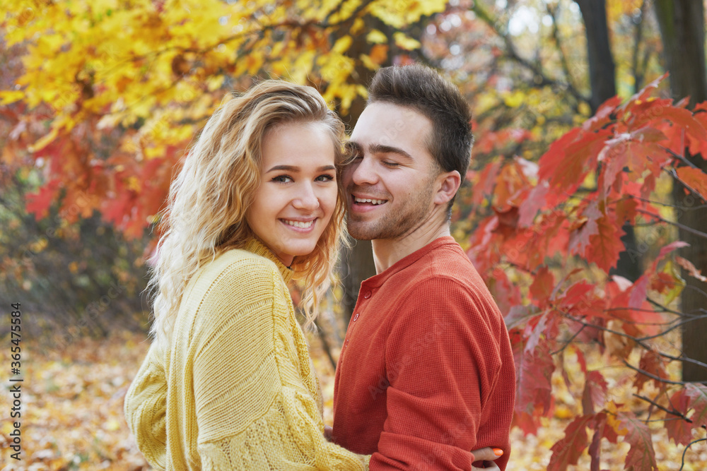 Young happy couple relaxing and loving in the autumn forest at sunset. Young happy couple relaxing and loving in the autumn forest at sunset.