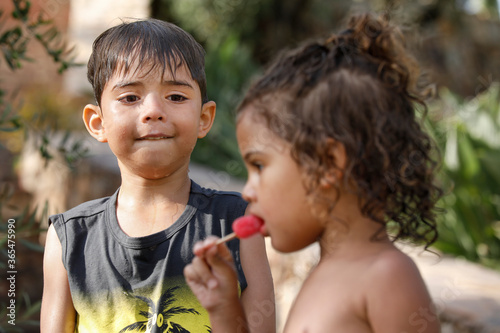 Fotografija due bambini di origine sudamericana sono fermi in un parco e la piu piccola mang