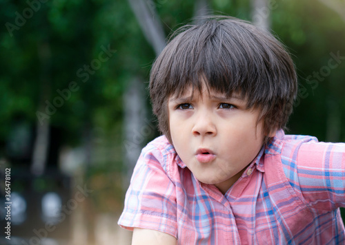 Head shot of little boy looking out with surprised face, Kid playing in the park, Child with funny face looking up.