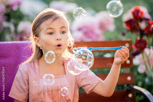 girl blows soap bubbles on the background of flowers in the garden