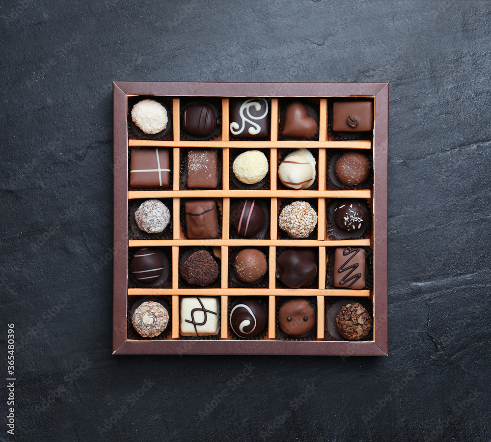 Box with delicious chocolate candies on black table, top view Box with delicious chocolate candies on black table, top view