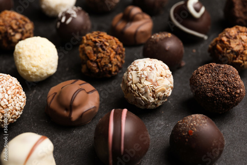 Different delicious chocolate candies on black table, closeup
