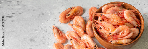Prawns in a wooden bowl on a light gray table. Lots of shrimp in a bowl. Shrimp close-up. Top view with space for text. Banner 