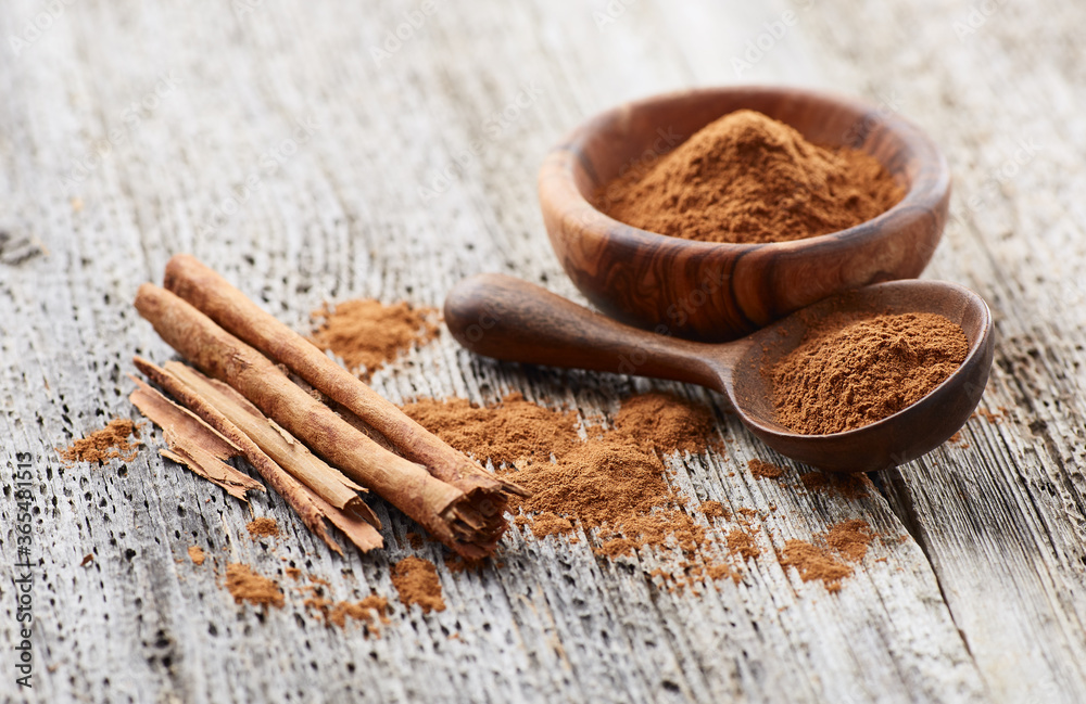 Cinnamon powder with cinnamon bark on wooden background Cinnamon powder with cinnamon bark on wooden background