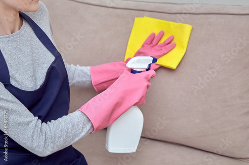 The girl applies a cleaning agent, household chemicals to the furniture.