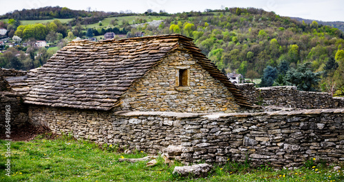 old rural house on a hill build from rocks on a hill with a wall