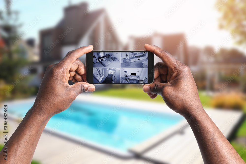 African-American man monitoring modern CCTV cameras on smartphone near his  house, closeup. Home security system Photos | Adobe Stock