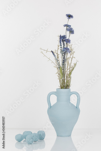 Bouquet of flowers in a blue vase on a white background with nuts