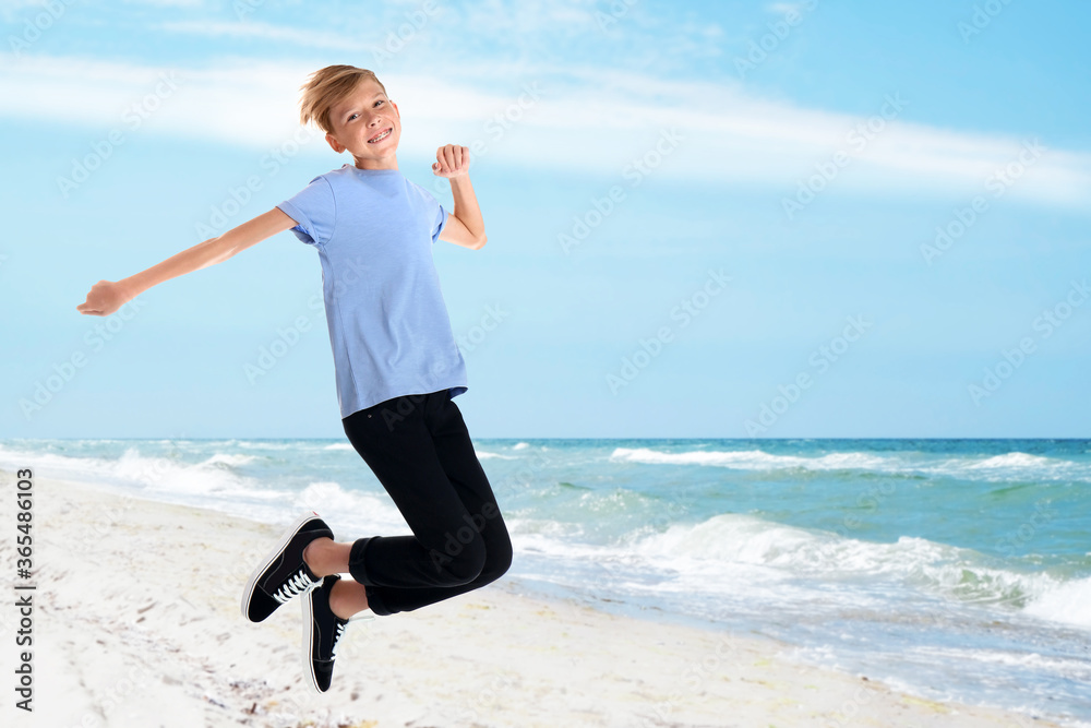 Happy school boy jumping on beach near sea. Summer holidays Happy school boy jumping on beach near sea. Summer holidays