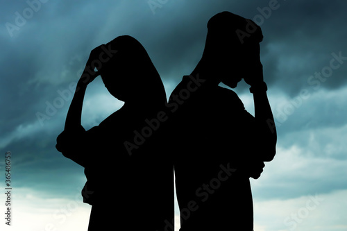 Картината върху платно Silhouettes of arguing couple against sky with heavy rainy clouds