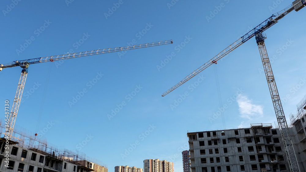 Two construction cranes and multi-storey concrete buildings under construction