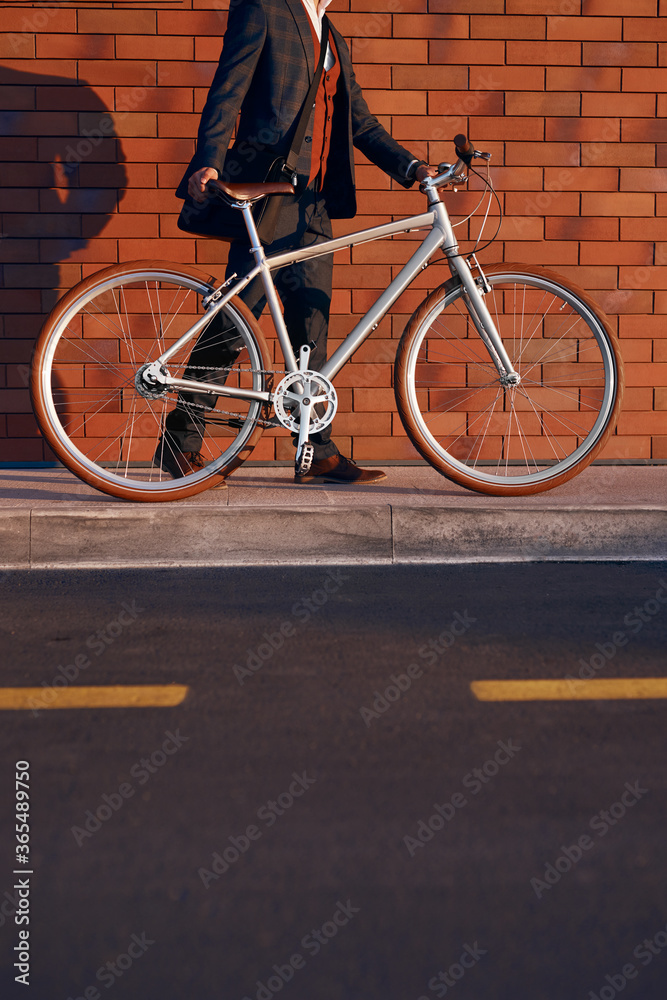 Crop businessman with bike walking on pavement