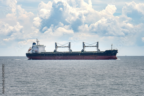 An old bulk carrier or bulker sails in the sea near shore
