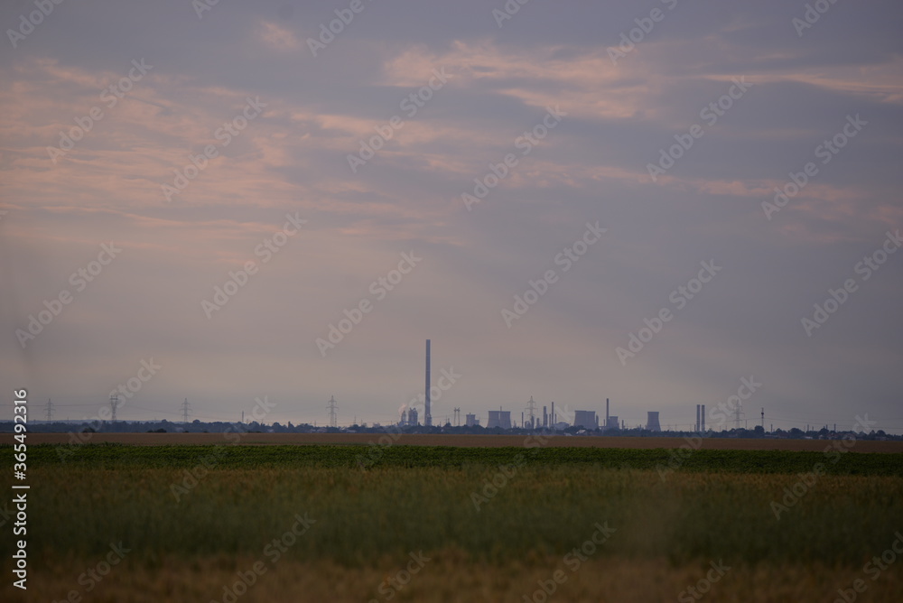 oil refinery seen on the horizon on the wheat field at sunset oil refinery seen on the horizon on the wheat field at sunset