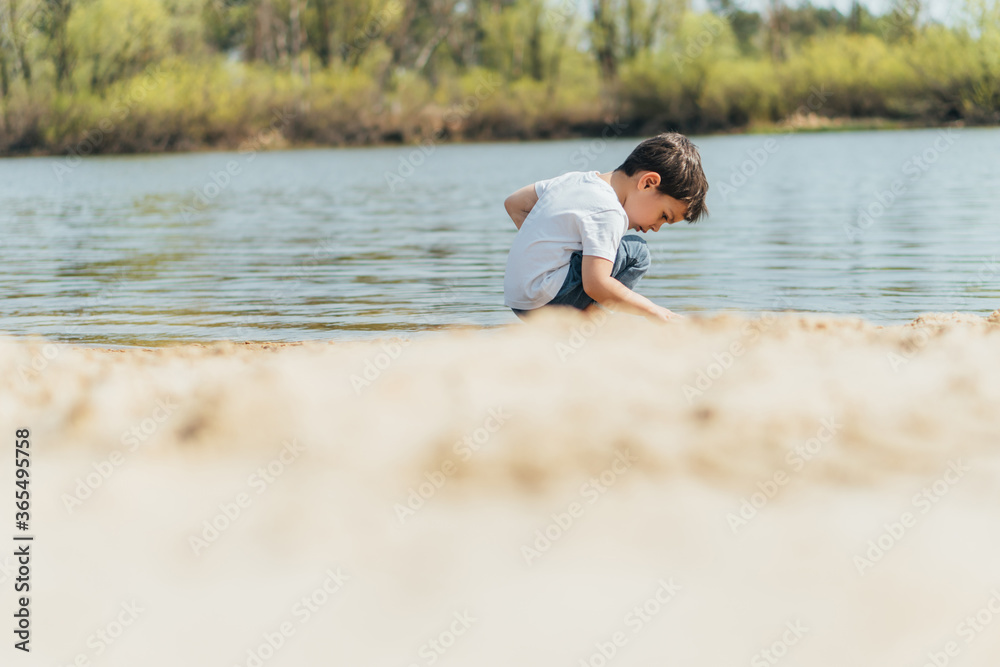 Selective focus of cute boy sitting near pond