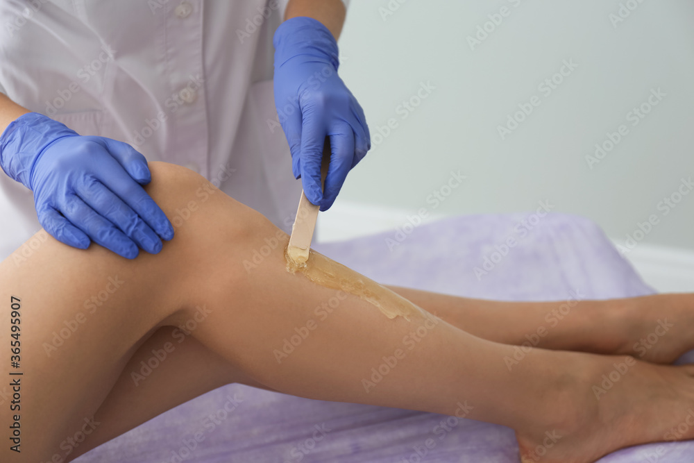 Woman getting wax epilation of legs in salon, closeup Woman getting wax epilation of legs in salon, closeup