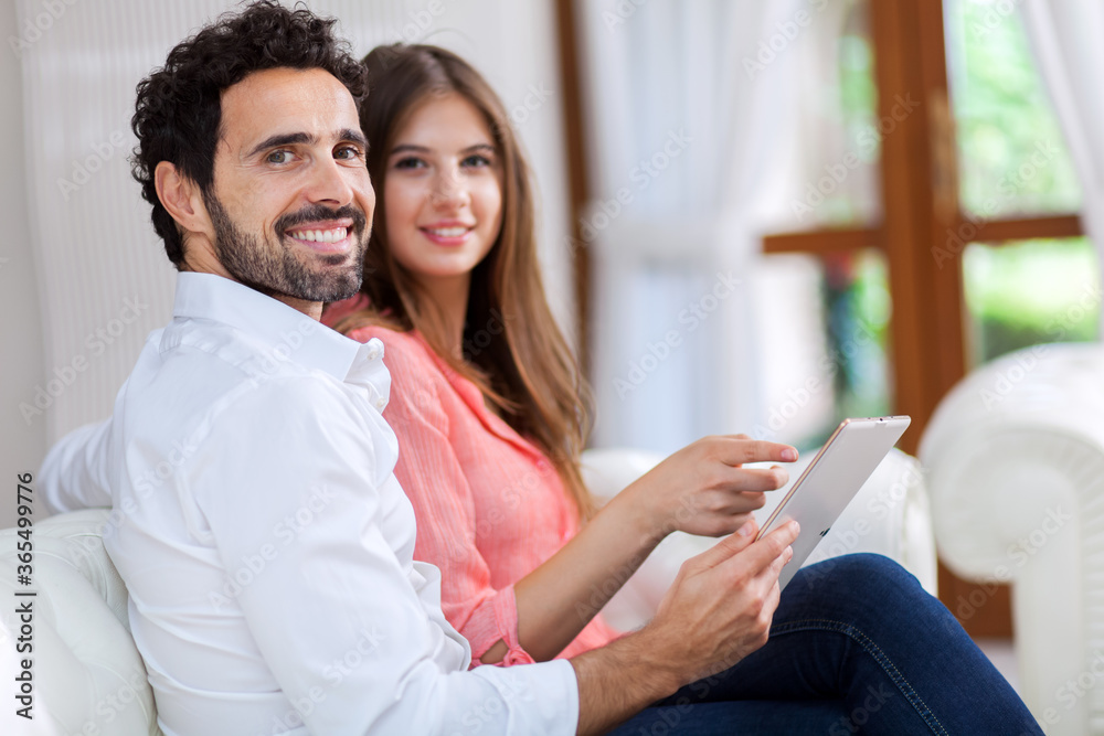In love couple using a tablet computer in their living room In love couple using a tablet computer in their living room