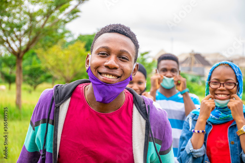 фотографія group of young black people wearing face masks, with physical distancing, smilin