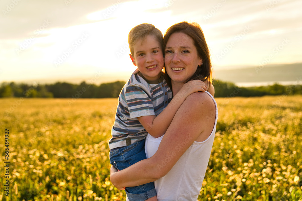 Obraz premium happy family of mother and child on field at the sunset having fun