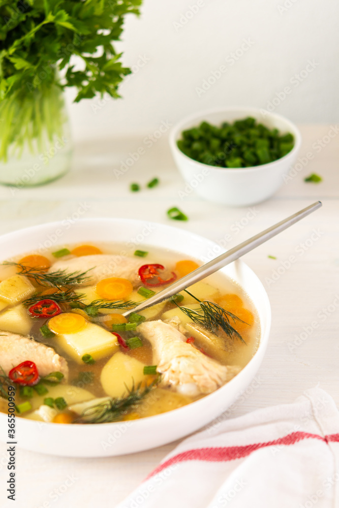 Chicken soup with fresh vegetables, chicken wings broth and young potatoes with onions and carrots, chopped green onions and parsley Chicken soup with fresh vegetables, chicken wings broth and young potatoes with onions and carrots, chopped green onions and parsley