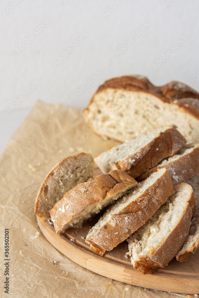 Loaf of homemade bread with sliced bread from wheat and seeds on parchment paper