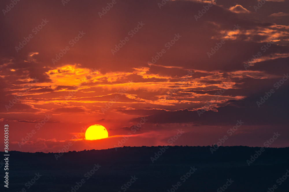 Stunning sunset over Varna suburbs  in the far distance, Bulgaria. Sun hidden behind clouds, rays passing through them. Landscape, cityscape, travel concept. Selective focus, copy space. Silhouettes. 