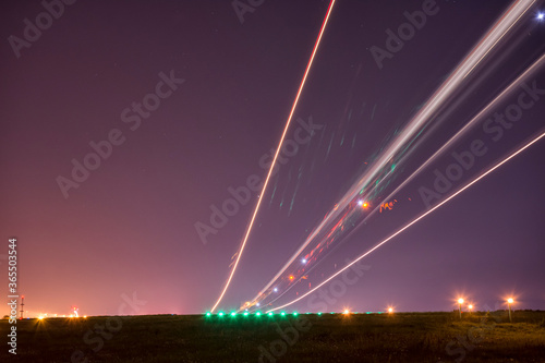 Ligth trails of a taking off airplane on long exposure at night.  horisont litted by the nearby city. Sky covered with shy stars.