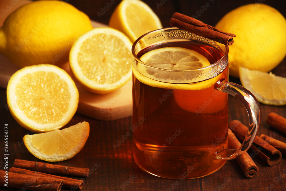 A mug with hot tea with lemons and cinnamon sticks A mug with hot tea with lemons and cinnamon sticks