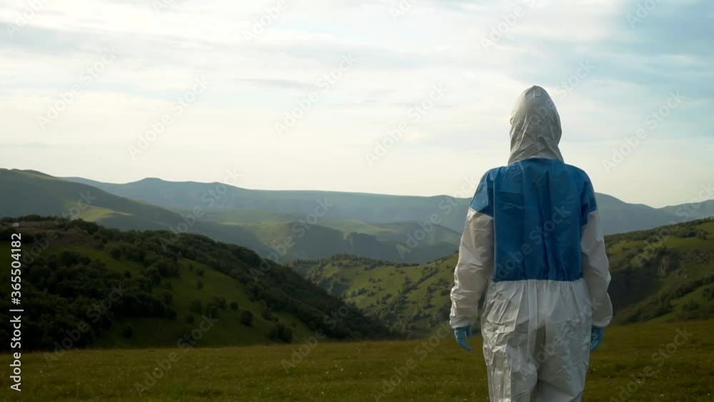 a man in a protective biological suit stand in the mountains a man in a protective biological suit stand in the mountains