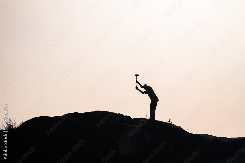 African man breaking stones - silhouetted 