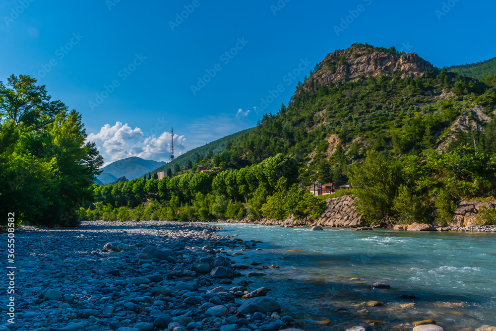 A picturesque landscape view of the French Alps mountains and the valley of a powerful alpine river Var on a sunny summer day