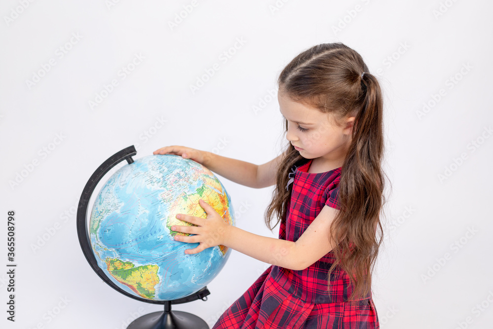 little girl school girl 7 years old sitting in a red dress with a globe on a white isolated background, place for text, September 1, knowledge Day little girl school girl 7 years old sitting in a red dress with a globe on a white isolated background, place for text, September 1, knowledge Day