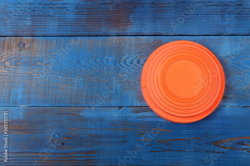 Slika na platnu Orange flying target plate against the blue wooden background