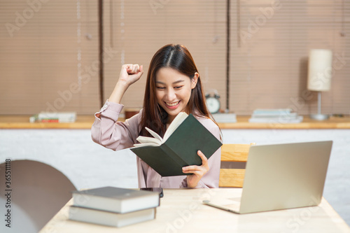 Young Asian woman feeling happy and excited while reading book for start small business at home